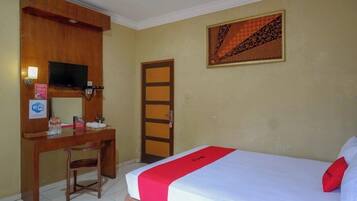 A hotel room with a bed, a desk, a television, and a door.
