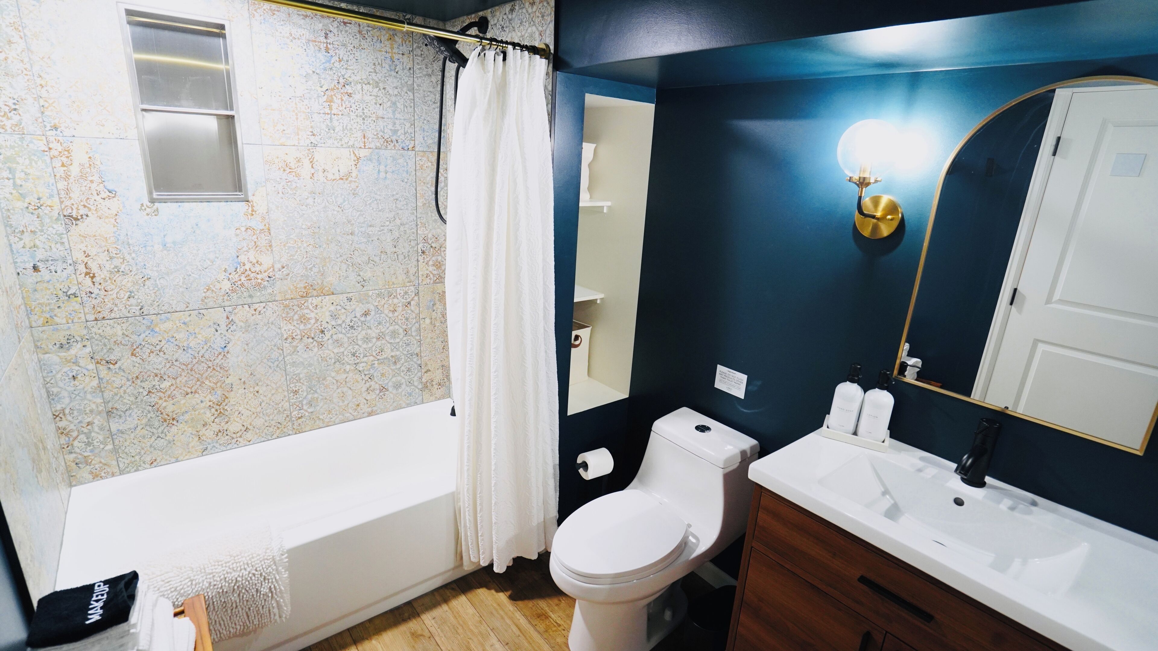 A bathroom with a bathtub, toilet, sink, and a mirror.