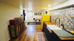 A compact kitchen with a wooden floor, a small dining area, and a colorful mosaic backsplash. - Walk to Music, Cafe, Bars, Food & Hospital in Central Denver. Turo + 420 ok!  (Denver)