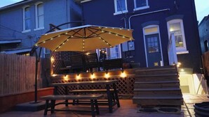 An outdoor patio area with a wooden table and bench, an umbrella, and string lights. - Walk to Music, Cafe, Bars, Food & Hospital in Central Denver. Turo + 420 ok!  (Denver)
