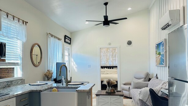 A modern kitchen with a central island, a dining area with a sofa, and a living room with a TV.