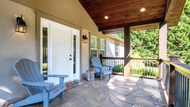 A covered porch with Adirondack chairs, a stone floor, and a wooden ceiling. - New Vacation Rental-Charming Mountain Home on 2 acres-20 mins to Downtown AVL (Leicester)