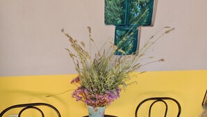 A small round table with two chairs, a vase with dried flowers, and a decorative wall piece. - Home & Gardens 2-Bed Villa in Sevasti, Katerini (Katerini)