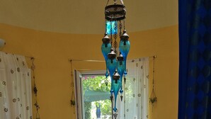A room with a patterned carpet, a central table with a decorative lamp, and a view through a window. - Home & Gardens 2-Bed Villa in Sevasti, Katerini (Katerini)