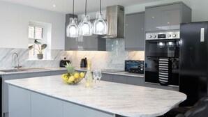 A modern kitchen with a marble countertop, stainless steel appliances, and pendant lighting. - Field View 5-Bed House - free parking (Burton upon Trent, Staffordshire, United Kingdom)