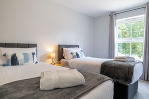 Una habitación de hotel con dos camas, una ventana con cortinas y una lámpara de noche.
