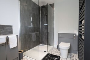 Un baño moderno con ducha de vidrio, inodoro y lavamanos.