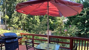 Une terrasse avec une table et des chaises, un barbecue et un parasol.