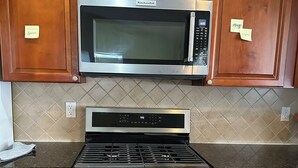 Une cuisine dotée de meubles en bois, d’un four à micro-ondes en acier inoxydable, d’une cuisinière à gaz et d’un four traditionnel.