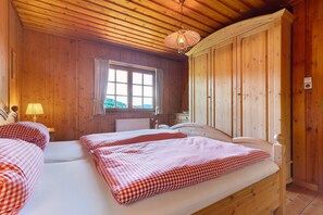Une pièce de cabane en bois avec deux lits, une fenêtre et un plafond en bois.