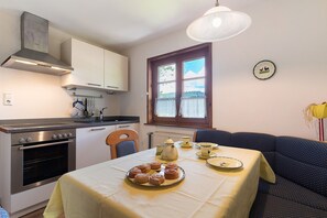 Une cuisine compacte équipée d’une cuisinière, d’un four et d’un coin repas avec une table dressée pour deux personnes.