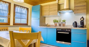 Una cocina con armarios azules, una mesa de comedor de madera y sillas.