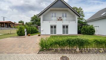 A two-story house with a balcony, a paved driveway, and a well-maintained garden.