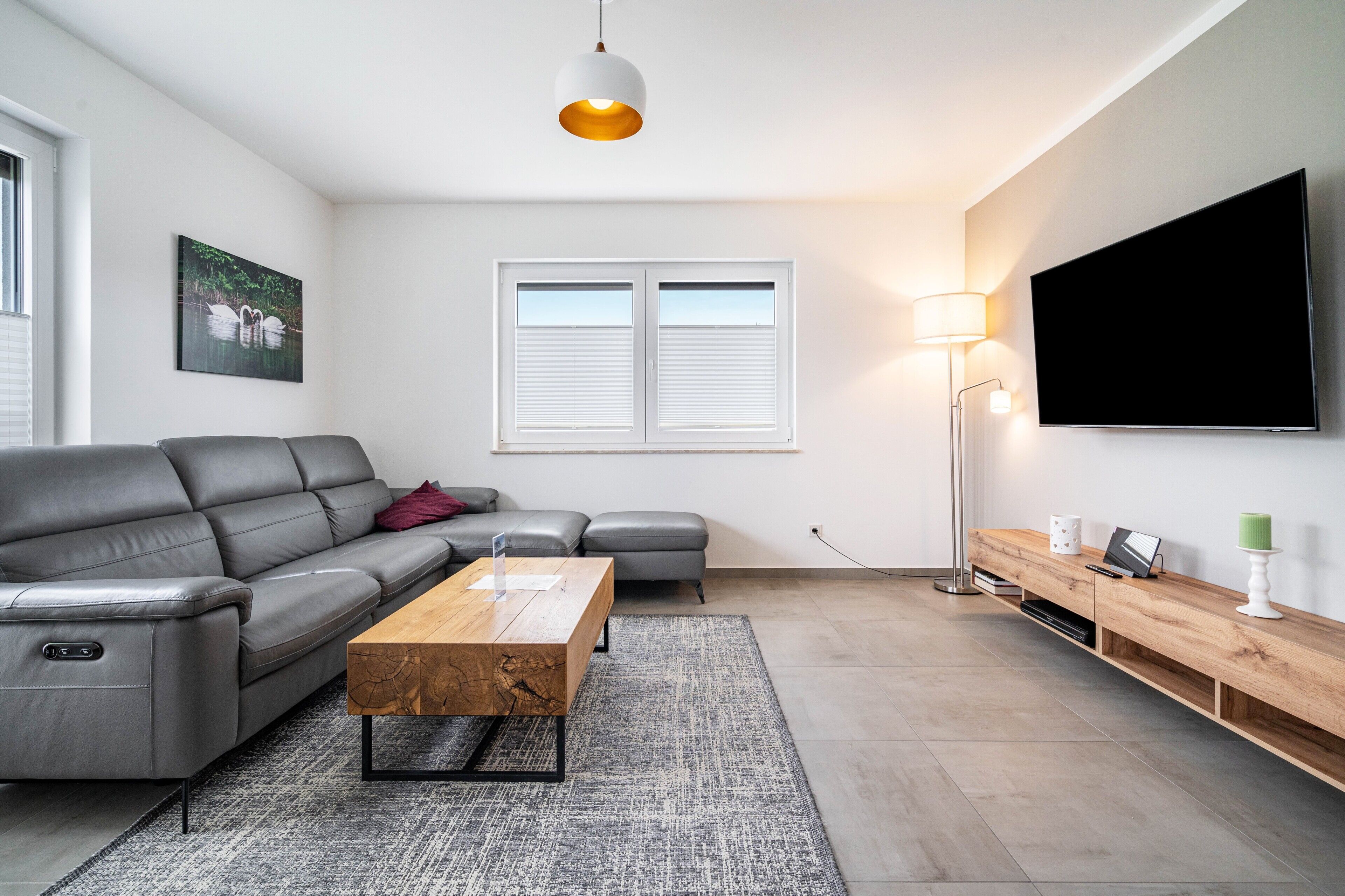 En moderne stue med sofa, sofabord, fjernsyn og lampe.