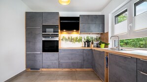 Una cocina moderna con gabinetes grises, encimera de madera y una ventana con vista a follaje.