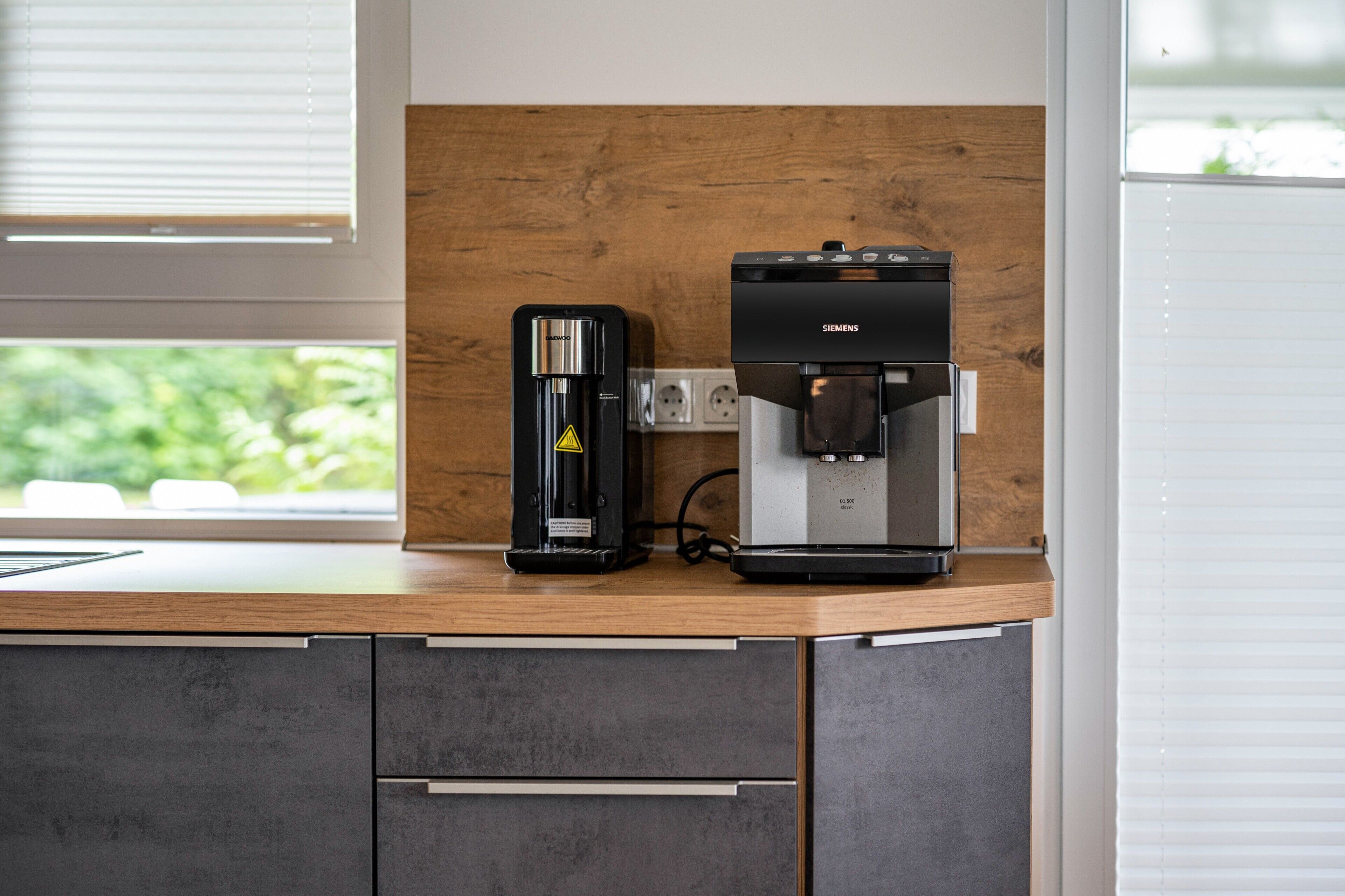 Et køkken med kaffemaskine og en Siemens espressomaskine på en træbordplade.