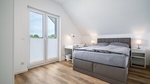 Un dormitorio con cama, mesitas de noche, un escritorio y una ventana con persianas.
