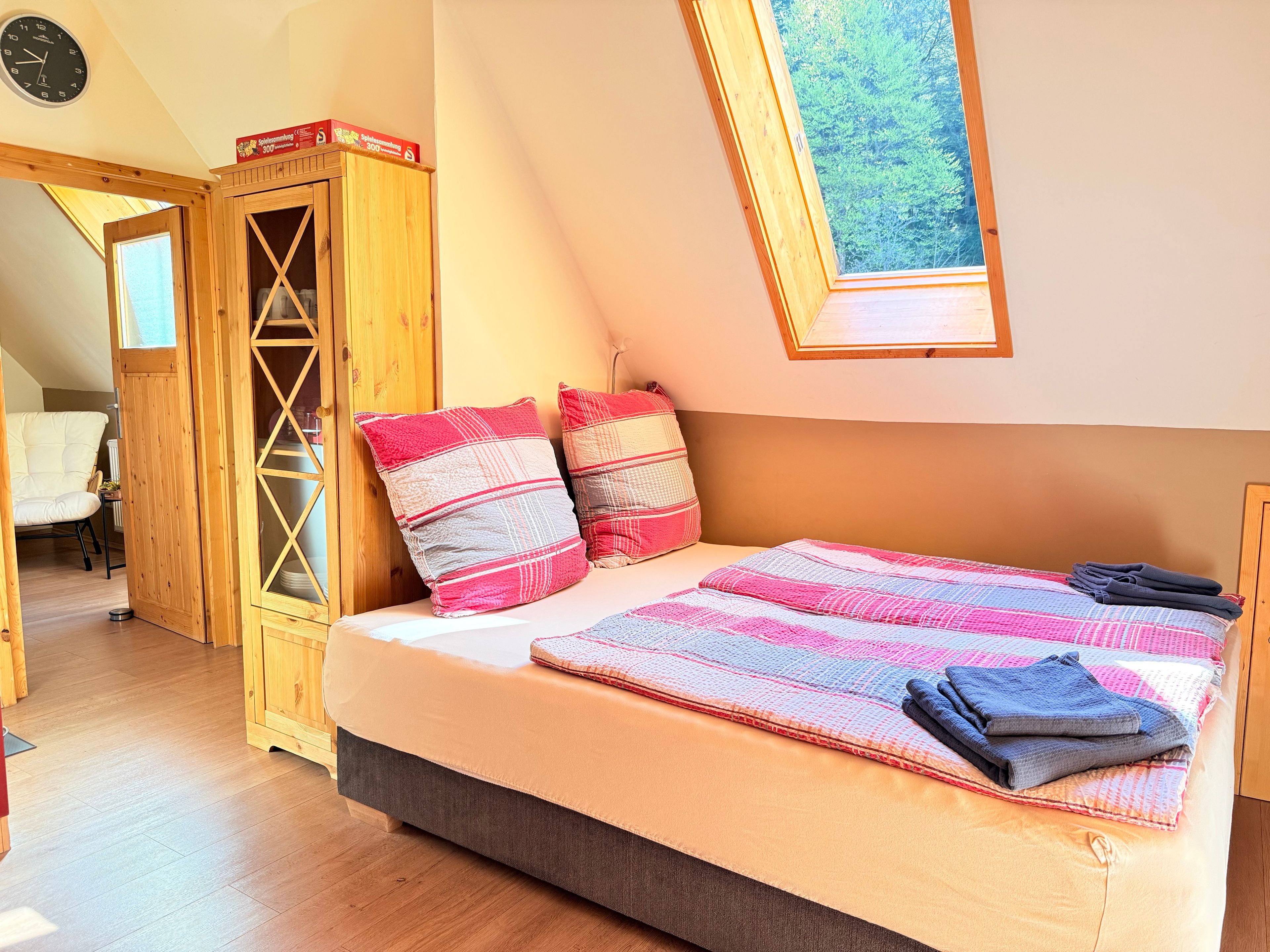 Ein Schlafzimmer mit einem Bett, Kissen, einem Fenster und einem Holzschrank.