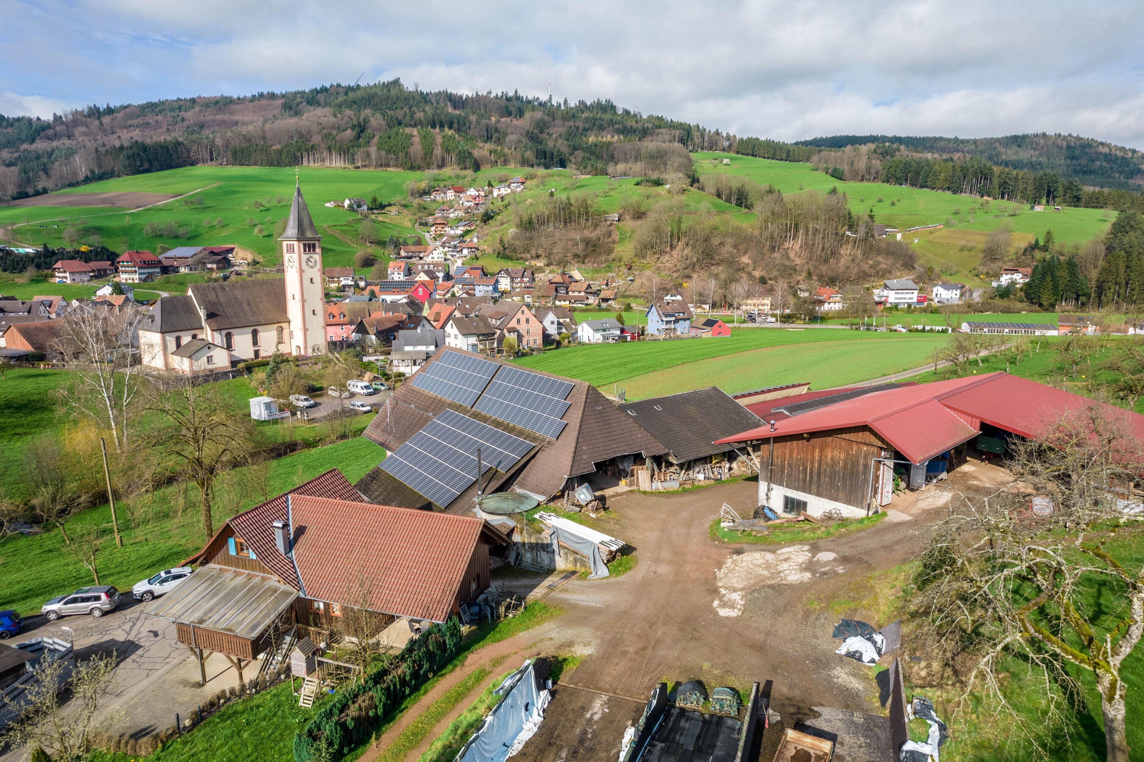 A rural village with a church, solar panels, and a dirt road.
