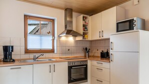 Una cocina con estufa, horno, microondas y ventana con persianas.