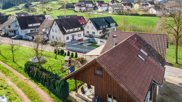 Un barrio residencial con casas, un parque infantil y una vista despejada de las colinas circundantes.