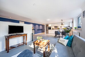 A modern living room with a TV, sofa, and coffee table. - Apartment 'Meerlust' with Private Terrace, Private Garden and Wi-Fi (Travemünde)