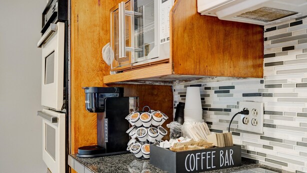 Una cocina compacta con una barra de café, una cafetera y una pila de vasos desechables.