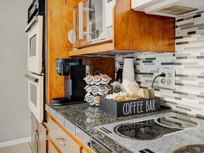 A compact kitchen with a coffee bar, a coffee machine, and a stack of disposable cups.