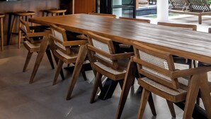 Une cuisine moderne avec des meubles en bois, une grande table à manger et deux lustres.