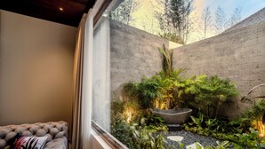 Un salon moderne avec une grande fenêtre, un canapé gris et une petite table en bois.