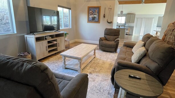 A spacious living room with a large sofa, a smaller armchair, and a coffee table. There is a television and a fireplace in the background. - BIRDSEYE VIEW (Helena)