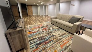 A modern living room with a sofa, a TV on a stand, and a colorful rug. - BIRDSEYE VIEW (Helena)