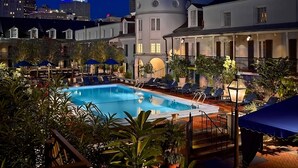 Un área de piscina con sillones de descanso y sombrillas, rodeada de edificios con cúpulas y campanarios.