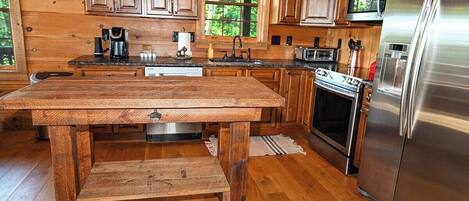 A wooden kitchen with a stainless steel refrigerator, wooden cabinets, and a wooden table.