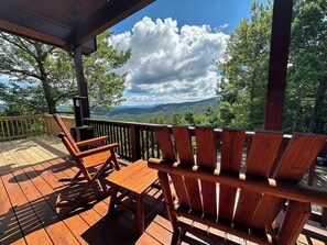 Une terrasse en bois avec un banc et une table en bois, offrant une vue sur un paysage montagneux.