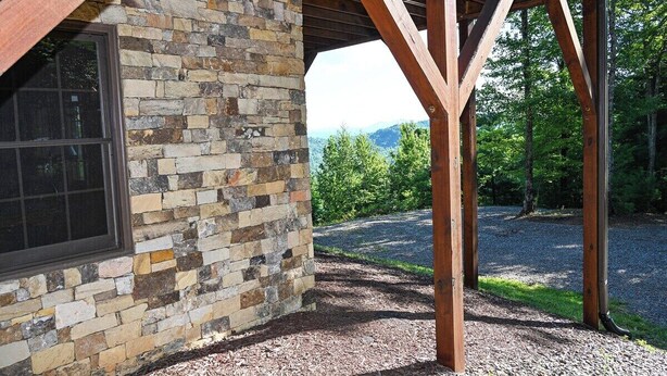 A stone building with a wooden pergola structure. - Mountain Lodge on 57 Acres • Hiking Trails • Private Lake • Hot Tub (Murphy)