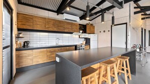 Eine moderne Küche mit Holzausstattung, einer zentralen Kochinsel mit Barhocker und einer schwarzen Arbeitsplatte.