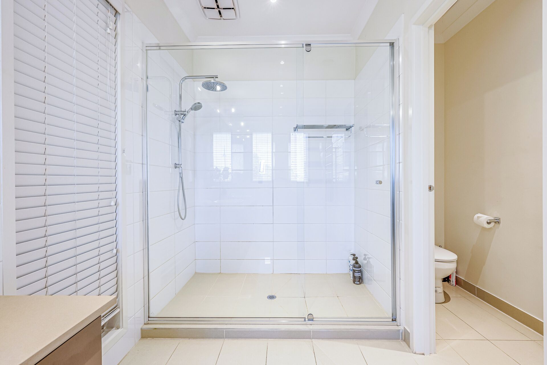 A glass-enclosed shower with a handheld showerhead and a wall-mounted faucet.