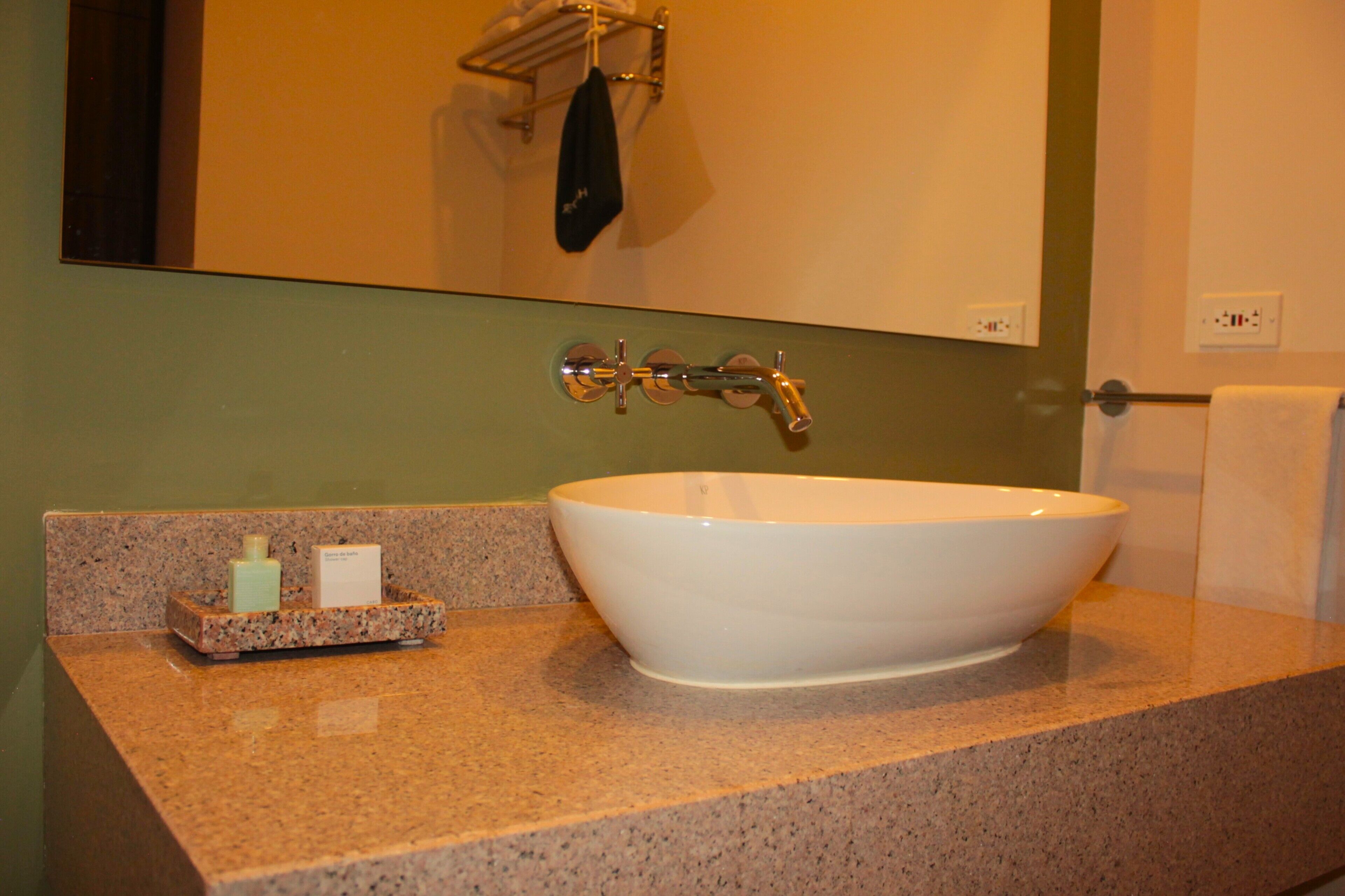 A bathroom with a white sink, granite countertop, and a mirror above the sink.