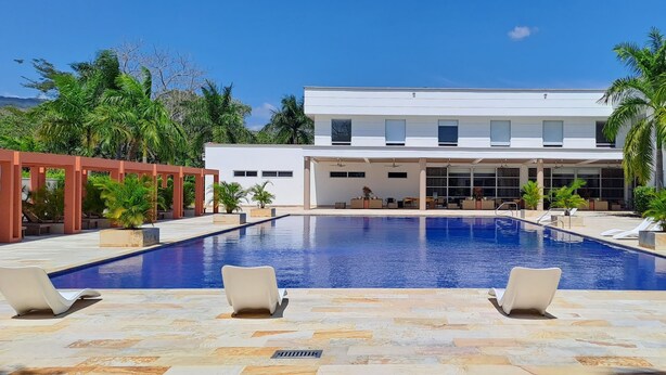 Un'area piscina moderna con una vasca rettangolare, lettini e una zona salotto coperta.