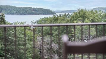 Un balcon avec vue sur un lac et des collines boisées.