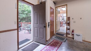 A hallway with a wooden door, a view of a deck with chairs, a rug, and a first aid station. - Lost Bridge Lodge on BEAVER LAKE! Across from POOL (Garfield)