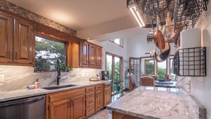 A kitchen with wooden cabinets, a marble countertop, and hanging pots. - Lost Bridge Lodge on BEAVER LAKE! Across from POOL (Garfield)