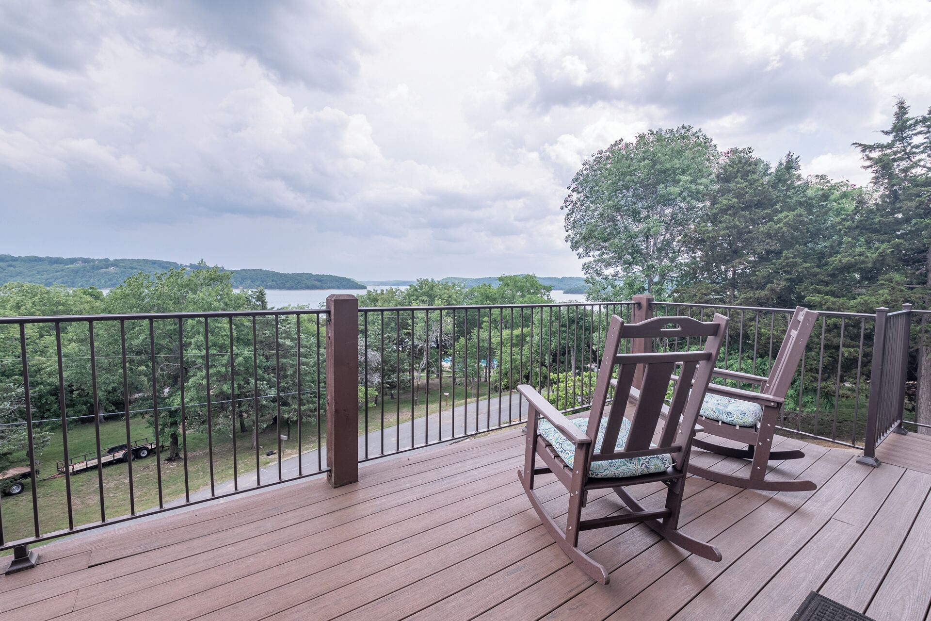 A wooden deck with two rocking chairs overlooking a lake and forested hills.