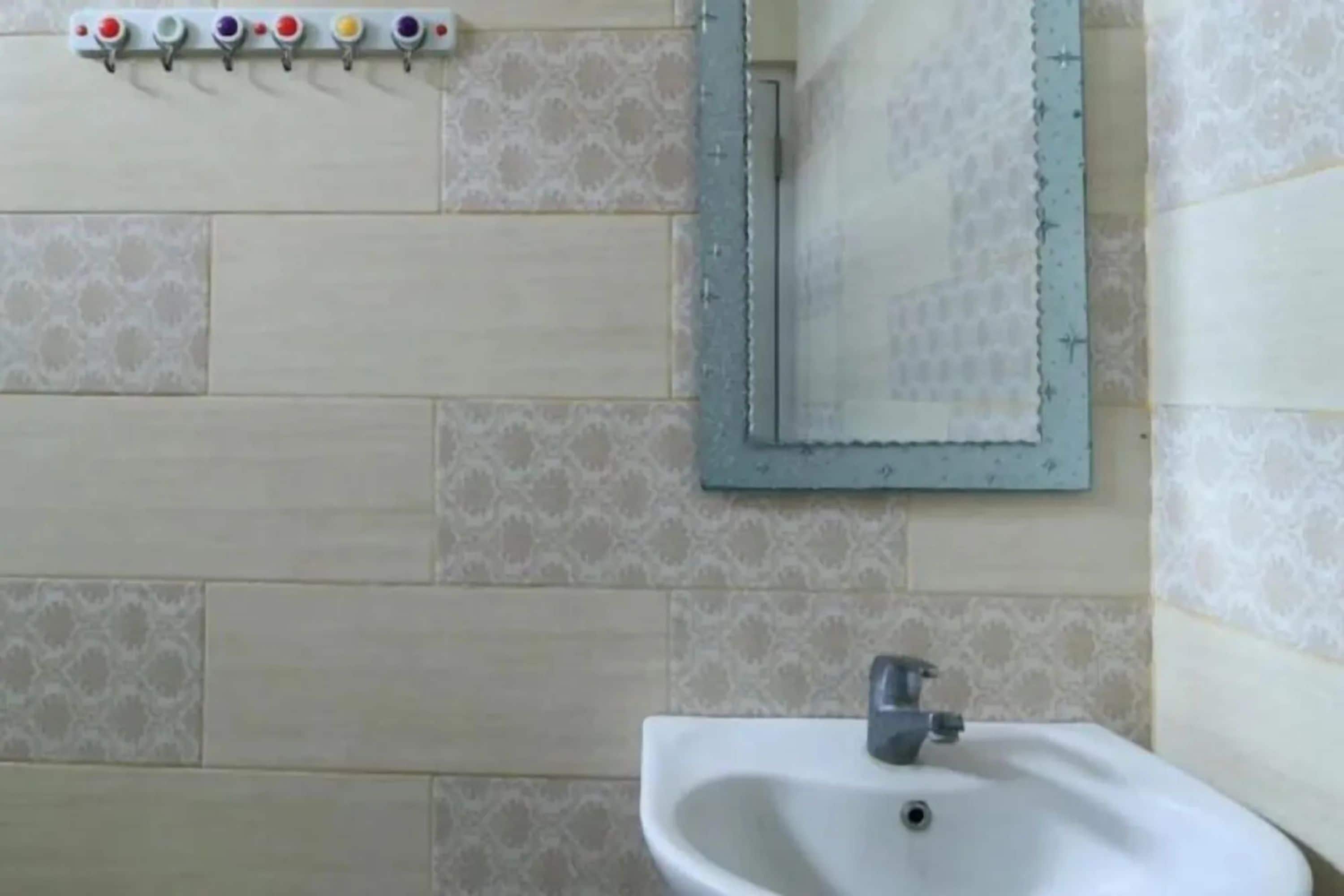 A bathroom with a sink, mirror, and a wall-mounted soap dispenser.