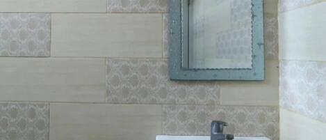 A bathroom with a sink, mirror, and a wall-mounted soap dispenser.