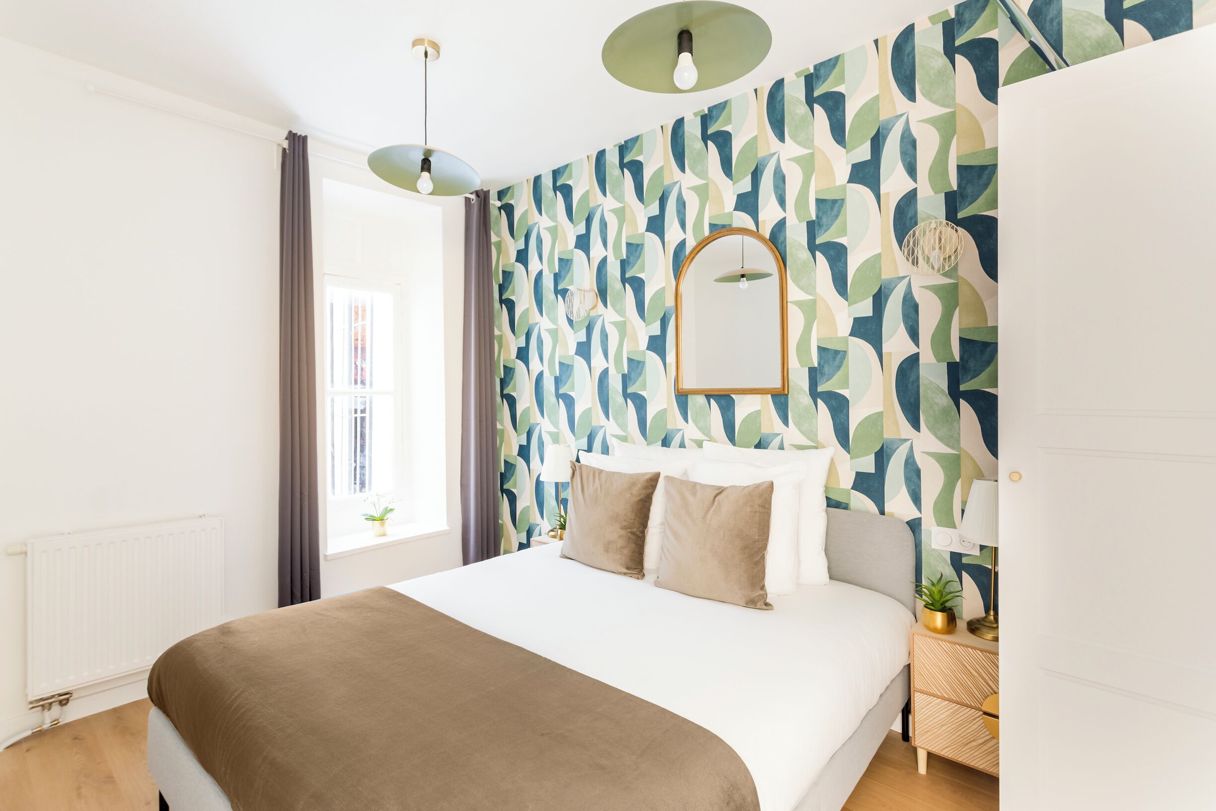Een moderne slaapkamer met een groot bed, een behang en een raam met gordijnen.