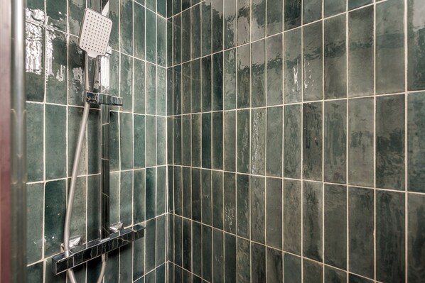 A tiled shower area with a handheld showerhead.