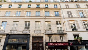 A multi-story building with a ground-floor shop named "A L'Heure Du Vin" and a black-framed door. - Merveil - Family Suite - Louvre - Sainte Anne (Paris)