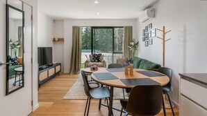 Ein modernes Wohnzimmer mit Essbereich, großen Fenstern und Blick auf Grünflächen.